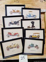 Overview photo showing all eight framed antique car illustrations arranged close together on a wooden surface.