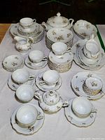 Full set of Johann Haviland Sepia Rose china laid out on table, showing plates, cups, bowls, serving pieces.