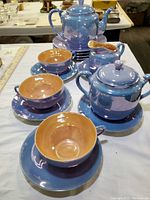 Photo shows the full tea set arranged on a table with a focus on the teapot, cups, and saucers.