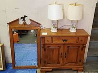 Maple wood cabinet with drawer and two door compartments, lined up next to matching maple wood framed mirror with decorative spire and eagle.