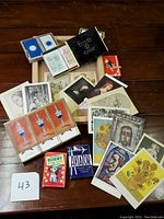 Top view of the lot on wood surface showing multiple decks of playing cards and assorted vintage art postcards