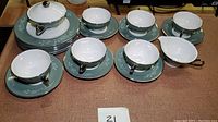 Full set view showing teacups on saucers, luncheon plates stacked, and covered creamer and sugar bowl included.