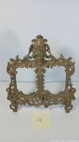 Front view of Victorian brass picture frame showing intricate details and central face motif