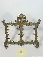 Front view of the ornate brass Victorian picture frame showing detailed baroque style scrollwork and floral designs
