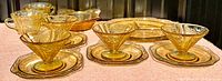 Photo showing the full set of amber yellow Depression glass pieces including cups, saucers, bowls, and large serving dish.