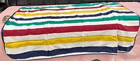 Full view of Hudson's Bay blanket laid flat showing multistripe pattern in yellow, red, green, navy blue on white background.