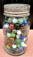 Front view of the fruit jar filled with colorful old marbles under a metal lid.