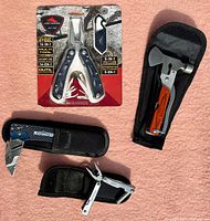 Photo of the three multi tools including High Sierra 14-in-1 multi tool in package, Mastercraft utility knife in case, and small multi tool with pliers in case.