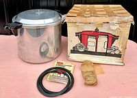 Photo showing the pressure cooker next to the original box, gasket, instruction manual, and paper insert.