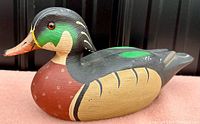 Front and side view of the vintage carved and painted wooden duck decoy showing detailed carving and paintwork with a reddish-brown breast and green head highlights.