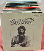 Photo showing a large stack of vinyl records behind Eric Clapton Crossroads 4 CD set.