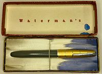 Top view of the Waterman Taperite Crusader fountain pen in its original box showing grey barrel and brushed gold aluminum cap with chromed clip inside a vintage Waterman's box with white and blue interior lining.