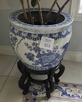 Overall view of the large blue and white ceramic planter on the dark wooden stand with the rubber tree plant inside
