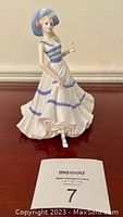 Full view of Coalport figurine showing woman in summer dress holding drink with MaxSold card in front