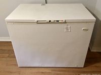 Full exterior view of white chest freezer on hardwood floor