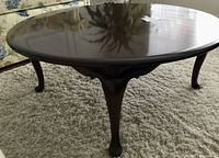 Full view of round coffee table on carpet showing mahogany finish and Queen Anne legs