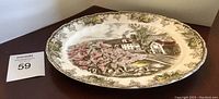 Full view of Johnson Brothers oval platter showing village green scene with pink blossoms and floral border, measuring about 11.75 x 9.5 inches.