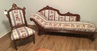 Both the chaise lounge and matching chair with oak carved wood and floral upholstery shown together in room