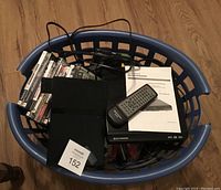 Basket containing Electrohome DVD player, remote, manual, PlayStation 2 and Xbox game cases, controllers, and headset