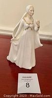 Full front view of Royal Doulton bride figurine standing on a reddish-brown surface.