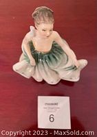 Front and top view of the seated figurine in green and gold gown with blue flower trim, showing full figure and pose.