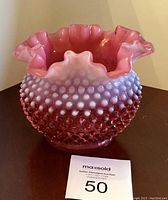 Front angle view showing raspberry hobnail texture and scalloped rim of the bowl with a MaxSold tag in front.