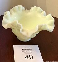 Front view of the vintage pale yellow Fenton glass bowl showcasing the ruffled edge and smooth interior surface