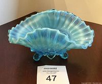 Front view of vintage aqua blue hobnail glass footed dish with ruffled edging on a table
