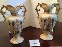 Photo of both Albany porcelain vases showing front side with ornate rose floral patterns, gold and green highlights, and curled handles.