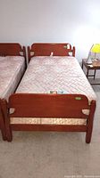 Front view of single wood bed frame with mattress and box spring, showing headboard, footboard, and base.