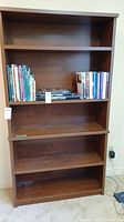 Full view of wooden bookcase with shelves and books for scale.