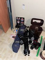 Overall view showing tripod, folding projector screen poles, portrait frame, camera bodies and lens cases