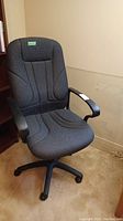 Full view of the office chair showing ergonomic padded backrest, armrests, and wheeled base.