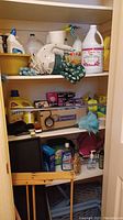 Photo showing multiple shelves stocked with cleaning agents, a boxed light bulb set, food storage containers, a hand vacuum and various household items.