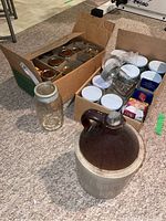 Photo of entire lot showing large pottery jug and two boxes of glass canning jars with lids