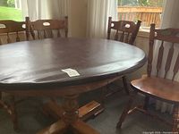 Oval dining table with protective vinyl cover and four chairs around