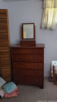 Front view of the five-drawer dresser with vanity mirror on top, showing overall condition and wear.