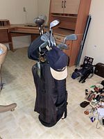 Full view of the golf bag standing on the floor loaded with golf clubs, showing some heads and shafts of clubs.
