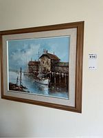 Framed original painting on wall showing boat at dock with buildings, signed G. Foreman.