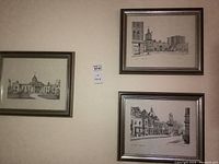 Three framed ink sketches of downtown Kingston, Ontario, mounted on wall.