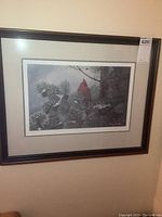 Framed signed and numbered print showing a cardinal on snowy pine branches in winter, with dark wood frame and beige matte.