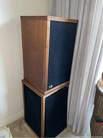 Pair of speakers stacked showing front fabric grilles and wood cabinets