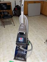 Front view of blue and gray Hoover SteamVac Clean Surge carpet cleaner with powered hand tool attached.