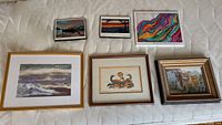 Overview of six framed artworks laid out on a surface including two smaller landscape images, one colorful abstract plaque, the Morrissey oil painting with wood frame, Norval Morisseau style print, and a third smaller framed painting.