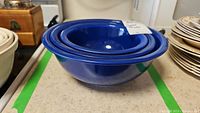 Nested set of three cobalt blue Pyrex bowls from a side angle, showing all bowls stacked inside each other.