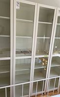 Full front view of white Billy bookcase showing two glass-paneled doors and six shelves