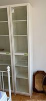 Front view of the white Billy bookcase with glass door, showing six shelves inside.