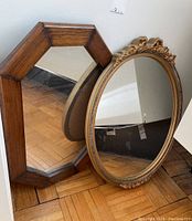 Two wall mirrors together showing octagonal wood frame mirror and oval gold decorative frame mirror