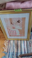 Framed print of a woman seated on a striped upholstered chair looking into a mirror with a gold frame, measuring approximately 18.5x14 inches.