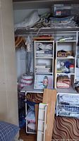 Photo of closet setup showing shelving units, folded fabrics, blankets on shelf, pillows, and storage baskets.